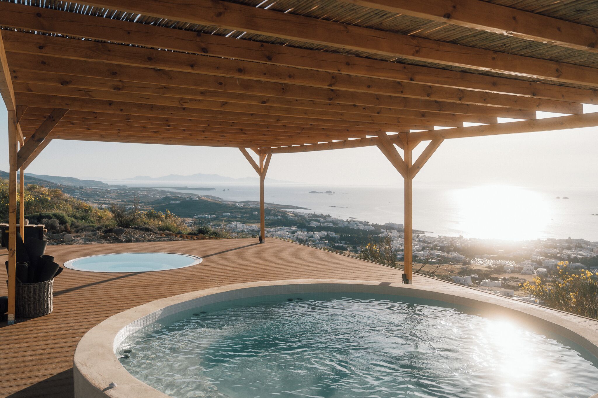 Terraza de madera con un jacuzzi y vista al mar.