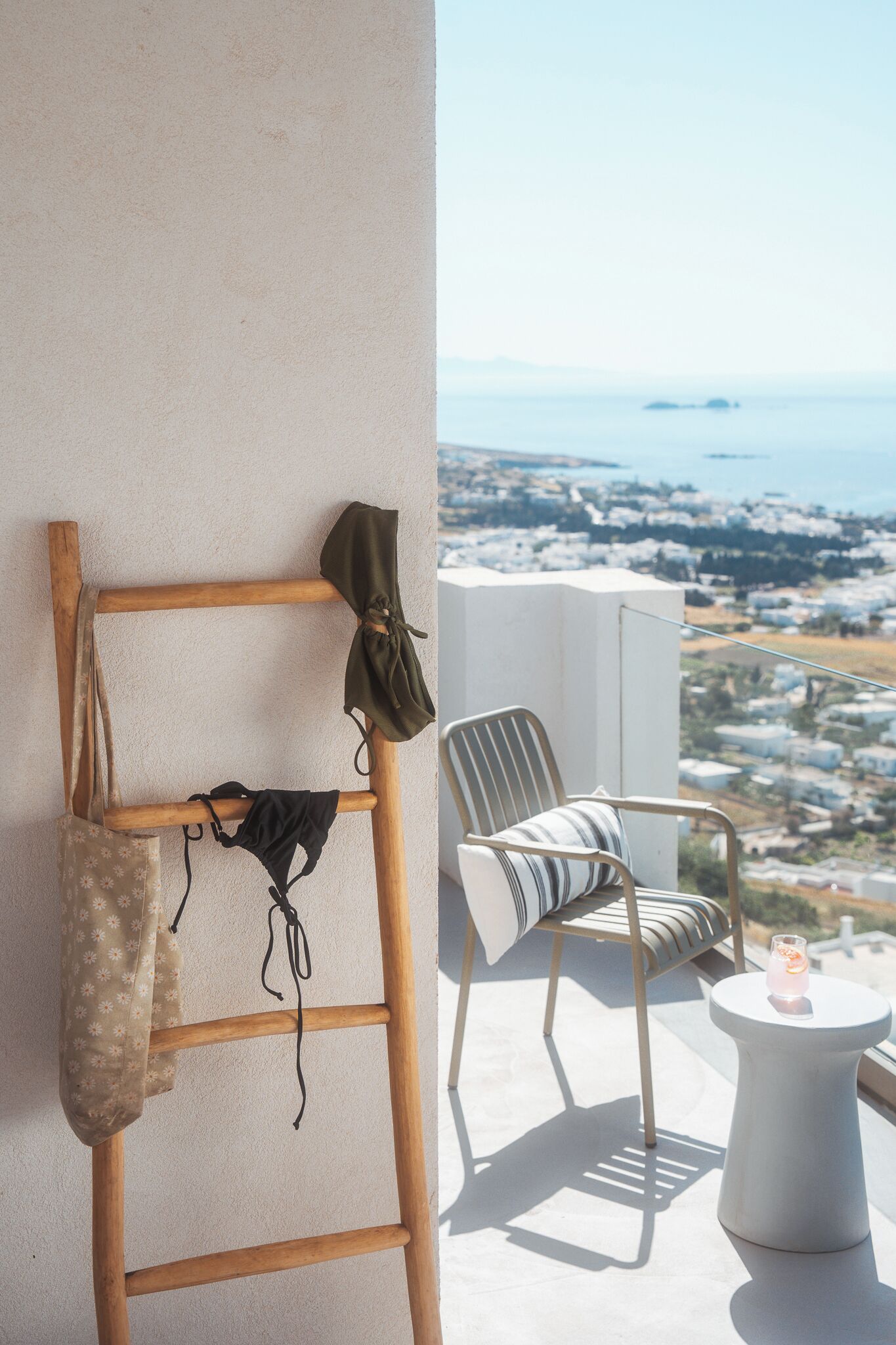 Un balcón con una escalera de madera, una silla a rayas y una mesita con una vela.