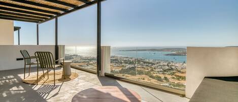 A balcony with a view of the sea and a cityscape.