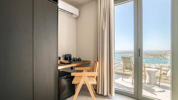 Una cocina moderna con estufa integrada, una zona de comedor con dos sillas y vistas al mar a través de amplios ventanales correderas.