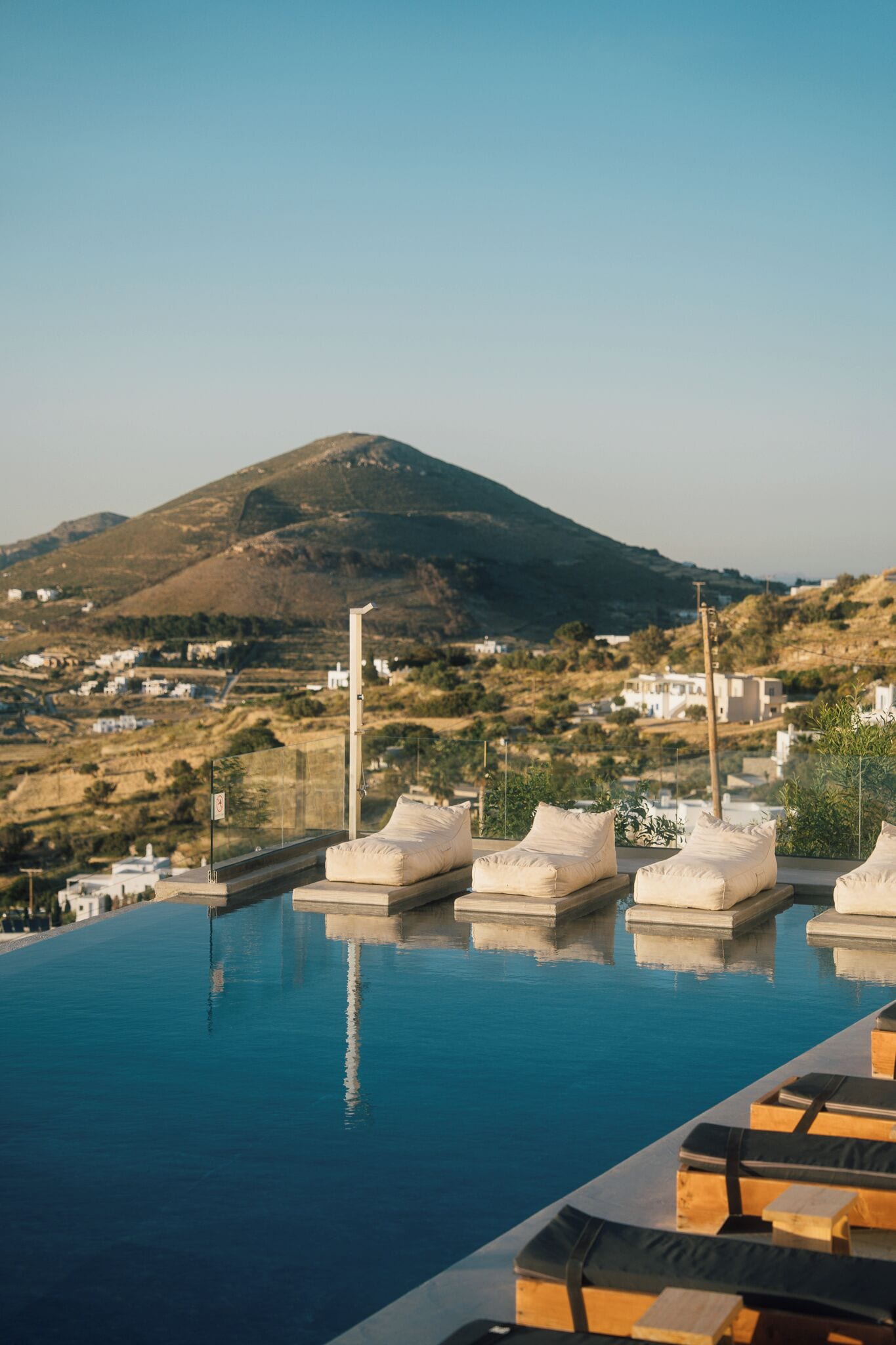 A pool with lounge chairs and a view of a mountain and buildings in the background.