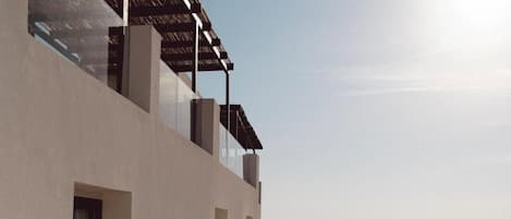 A modern building with a pool, a clear view of the sea, and a balcony overlooking the landscape.