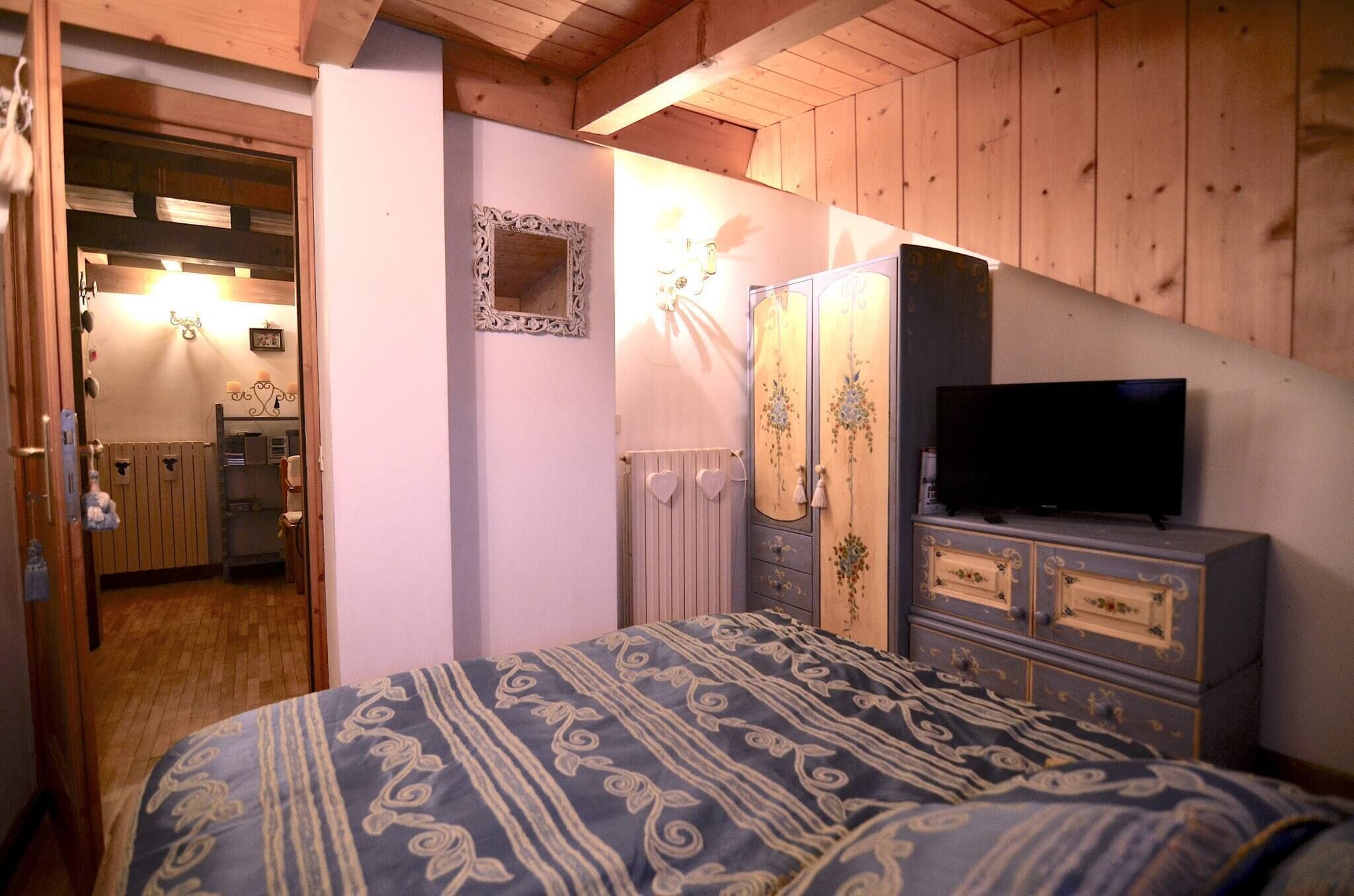 Quarto com cama, penteadeira, televisão e espelho.