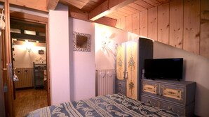 Ein Schlafzimmer mit Bett, Kommode, Fernseher und Spiegel.