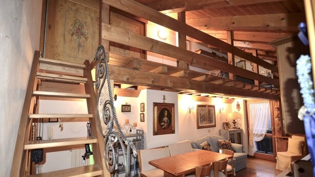 Ein Holzinnenraum mit Essbereich, Treppe und einer Couch.