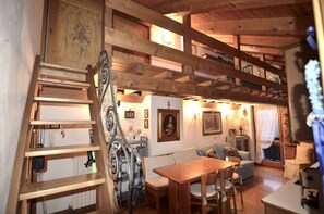 A wooden interior with a dining area, a staircase, and a sofa.