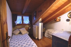 Une petite pièce agréable, dotée de deux lits, d’un radiateur et d’une fenêtre avec des rideaux.