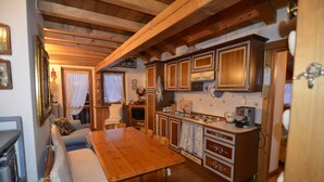 Eine gemütliche Küche mit Holzschränken, einem Esstisch und einer Couch.