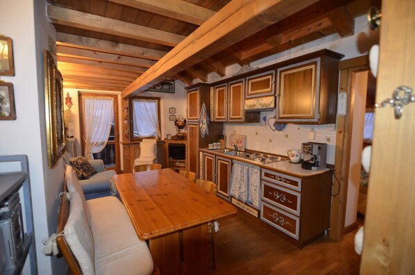 A cozy kitchen with wooden cabinets, a dining table, and a sofa.