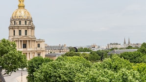 Un bâtiment historique doté d’un imposant dôme doré et d’une architecture classique, entouré d’une végétation luxuriante.