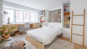 Une chambre à coucher moderne avec un grand lit, un bureau et une bibliothèque.
