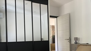 A bedroom with a bed, a wardrobe, and a door leading to another room. - Maison Avec Piscine (Saint-Raphaël)