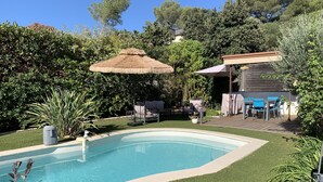 A swimming pool surrounded by artificial grass, with a patio area featuring outdoor furniture and a covered seating area. - Maison Avec Piscine (Saint-Raphaël)