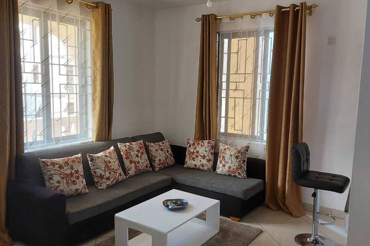 A modern living room with a grey sectional sofa, floral cushions, a white coffee table, and a black chair.