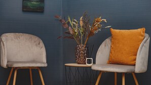 Dos sillas modernas con patas de madera y una pequeña mesa redonda con un florero de flores secas en el centro.