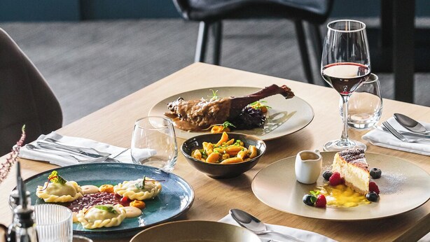 Una mesa de comedor servida con diversos platos, incluyendo albóndigas, un postre con frutos rojos y un tazón de sopa.