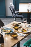 Une table à manger dressée avec différents plats, notamment des raviolis, un dessert aux fruits rouges et un bol de soupe.