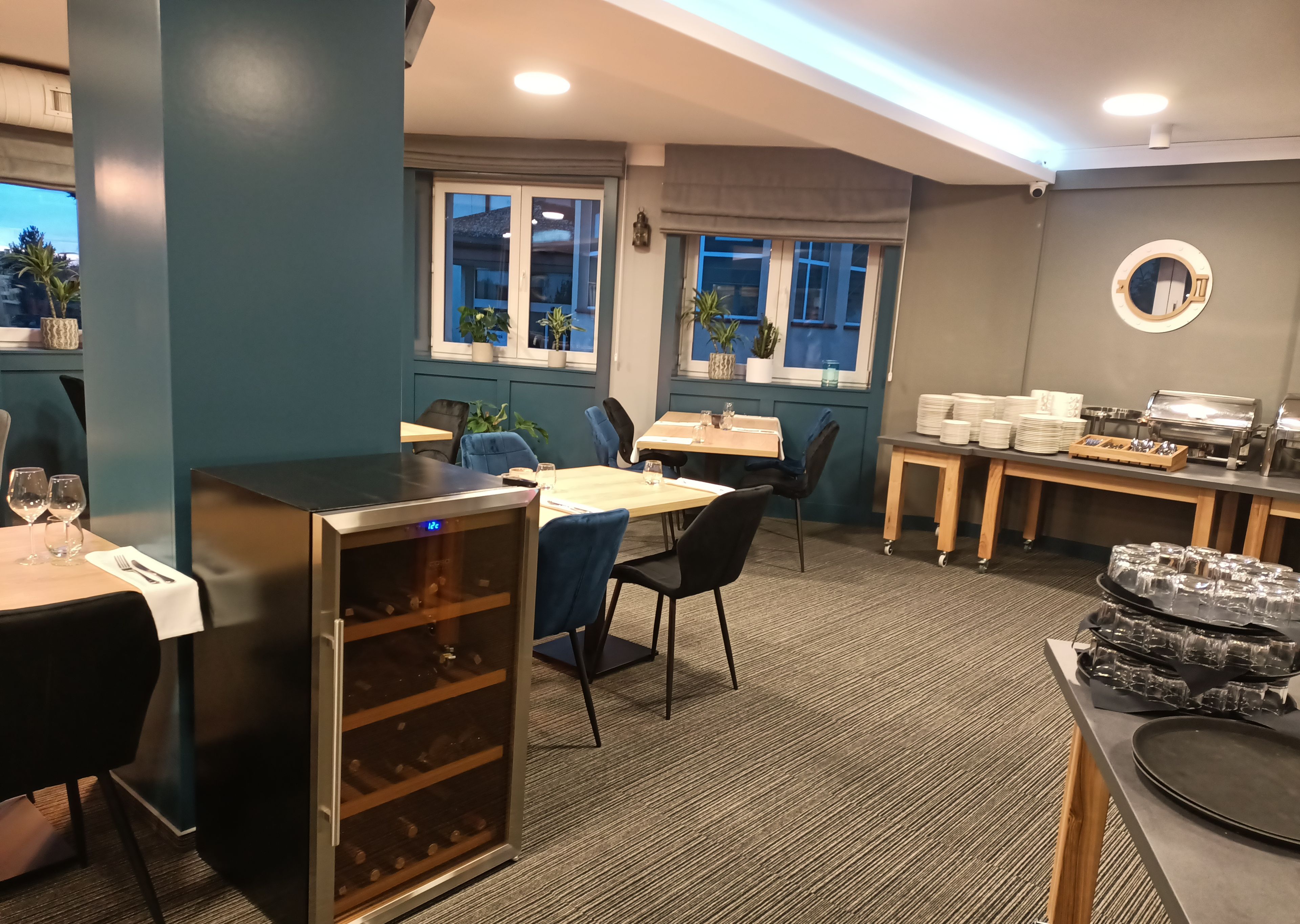 A modern dining area with tables, chairs, and a wine cooler.