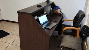 Un petit bureau avec un bureau en bois foncé, un ordinateur portable, une chaise et une petite statue posée sur le bureau.