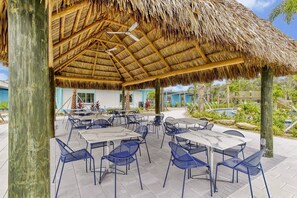 An outdoor patio area with thatched roof, tables, and chairs. - Magical Storey Lake Retreat | Your Disney Getaway (Kissimmee)