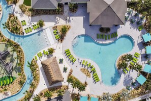 An aerial view of a resort with multiple swimming pools, sun loungers, and palm trees. - Magical Storey Lake Retreat | Your Disney Getaway (Kissimmee)