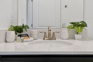 A bathroom with a white sink, a gold faucet, and two potted plants. - Magical Storey Lake Retreat | Your Disney Getaway (Kissimmee)