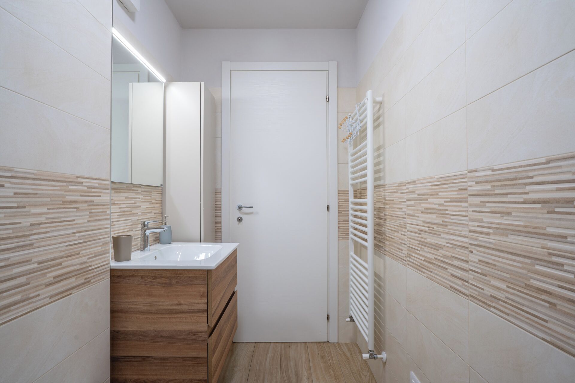Une salle de bain moderne avec un meuble-lavabo en bois, un lavabo blanc et un porte-serviettes.