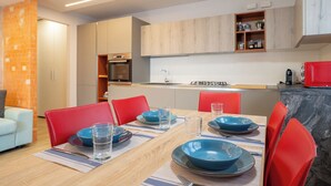 A modern kitchen with built-in appliances, a dining area with red chairs and blue plates, and a brick accent wall. - Il Balcone in centro di Via Manzoni (Barzio)