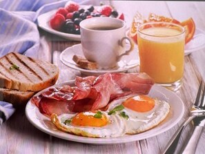 A breakfast setting with toast, eggs, bacon, coffee, and a glass of orange juice. - Vila Eduart (Ksamil)