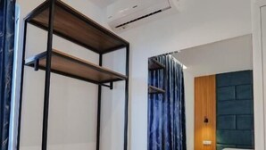 A modern bedroom with a wooden wardrobe, a mirror, a bedside table, and a blue ottoman. - Vila Eduart (Ksamil)