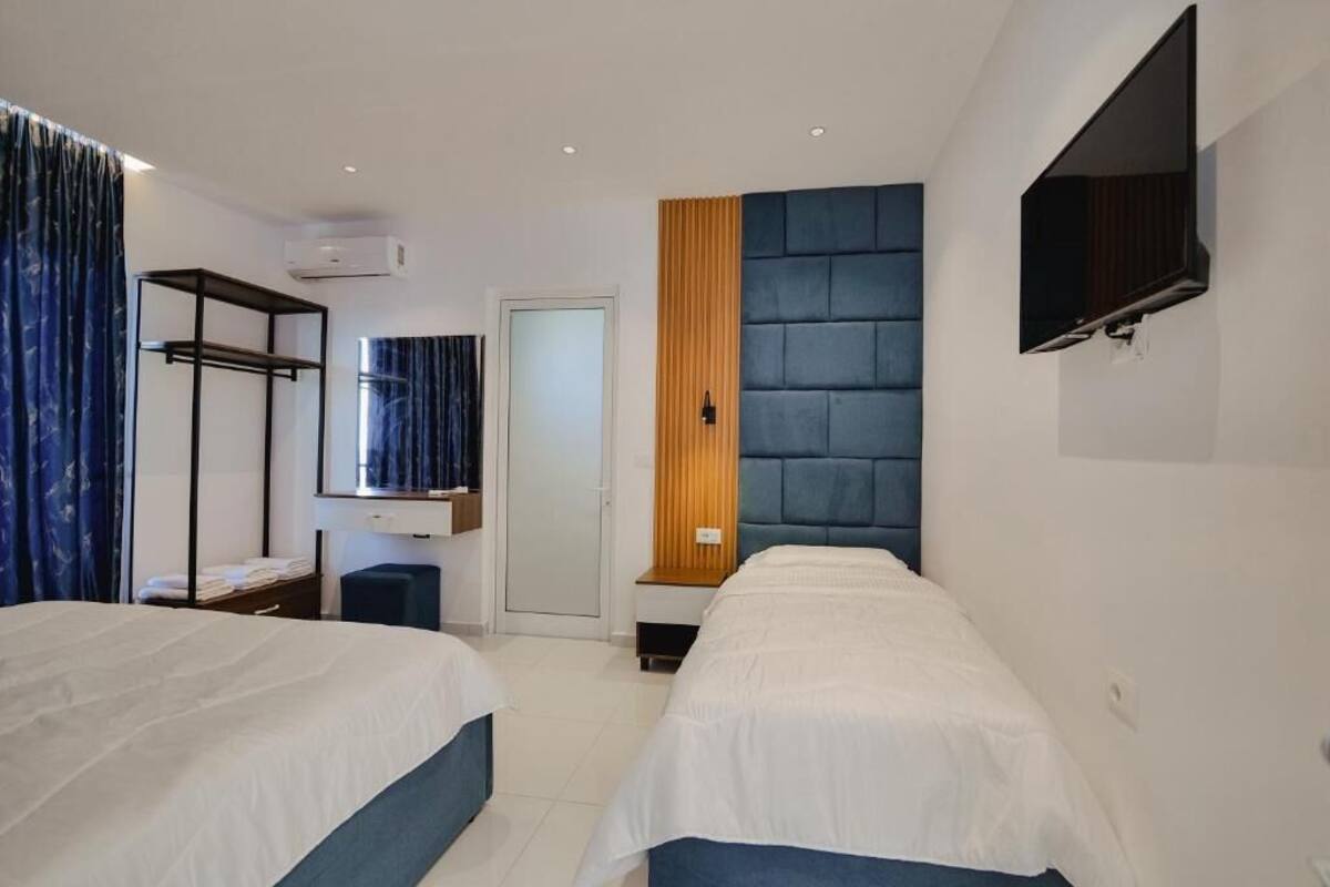 Une chambre d’hôtel avec deux lits, un téléviseur fixé au mur, une armoire et un miroir.