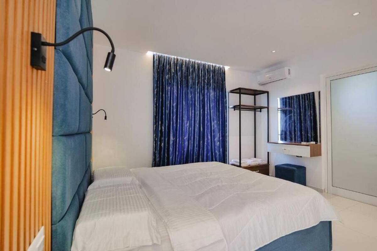 Une chambre moderne avec un lit, une armoire, un miroir et un rideau bleu.