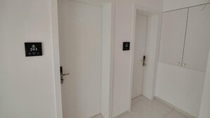 A hallway with white walls and doors, each marked with a number. - Vila Eduart (Ksamil)