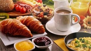 A breakfast setting with croissants, fruit, a bowl of cereal, coffee, and juice. - Vila Eduart (Ksamil)