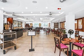 A spacious hotel dining area with multiple tables and chairs, a buffet station, and a counter with a menu display. - 234 Temple Tranquility: Triton Retreat- Luxury Palm Cove Apartment with Resort Pool & Oversized Balcony (Palm Cove)
