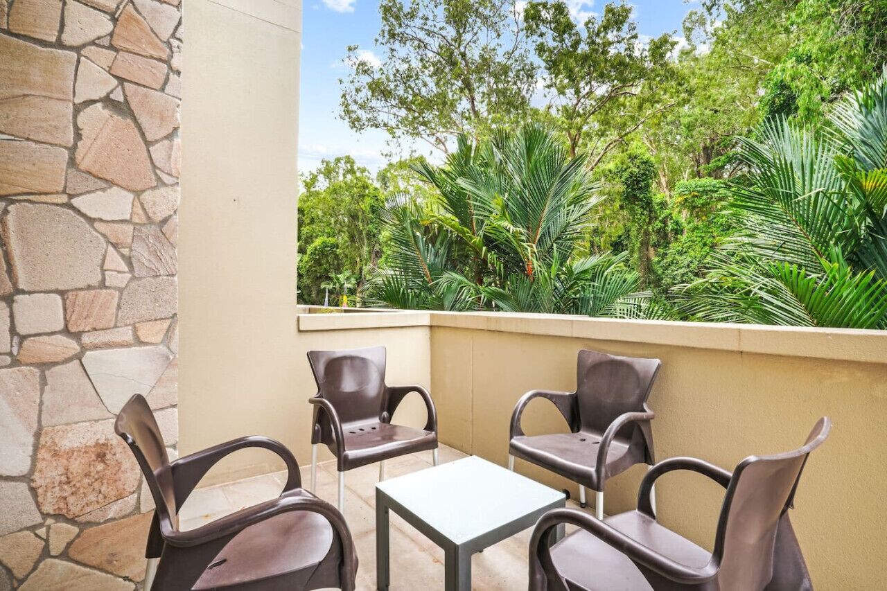 An outdoor seating area with stone walls and lush greenery in the background.