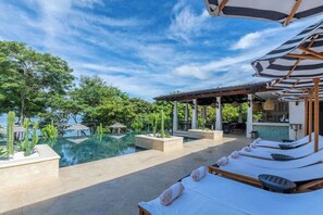 A poolside area with lounge chairs, a bar, and a view of the sea. - Trendy Condo with Stunning Ocean Views and Exclusive Beach Club Access in Las Catalinas (Las Catalinas)