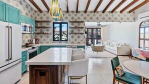 Una cocina amplia con gabinetes color turquesa, una isla central y un comedor con una mesa y sillas blancas.