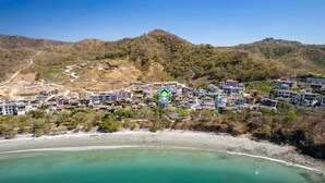 Un pueblo costero con playa, terreno montañoso y un conjunto de edificios.
