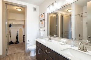 A modern bathroom with a double sink, a large mirror, and a walk-in shower.