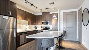 Una cocina moderna con electrodomésticos de acero inoxidable, una isla central con taburetes de bar y armarios de madera.