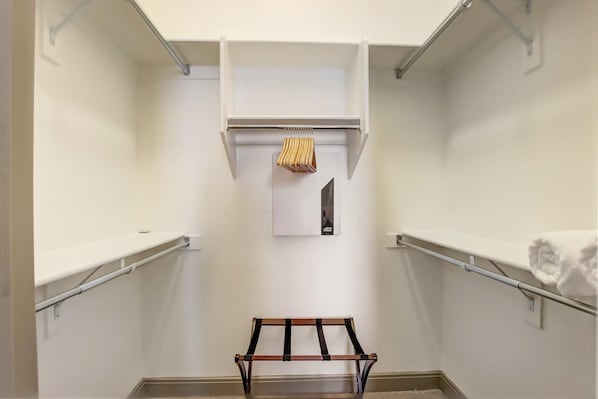 A walk-in closet with a bench, shelves, and hanging space.