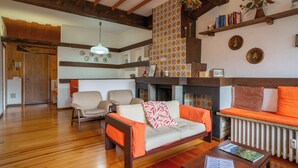 A cozy living room with a sofa, chairs, a fireplace, and a bookshelf.