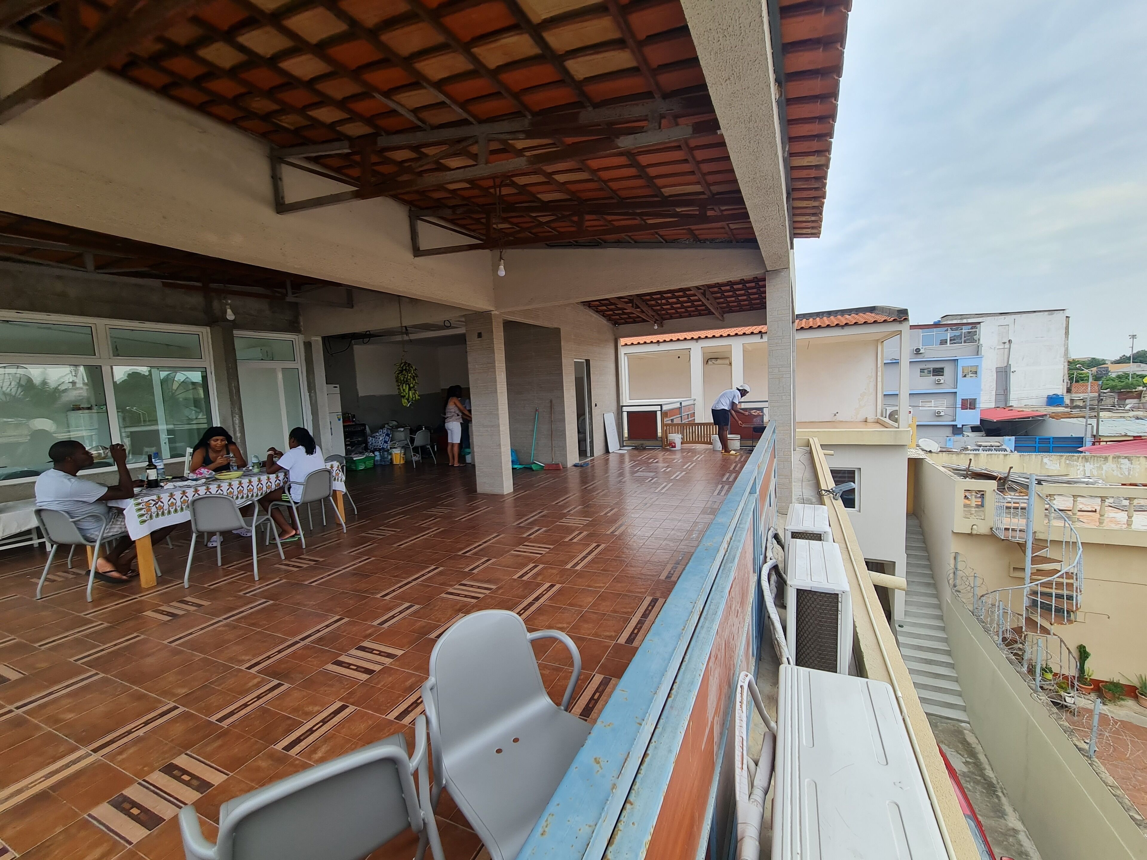 A covered outdoor area with a tiled floor, tables, and chairs.