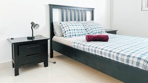 A neatly made bed with a checkered bedspread, a pillow, and a rolled-up towel. - Remarkable 5-bed Apartment in Kilamba - Luanda (Belas)