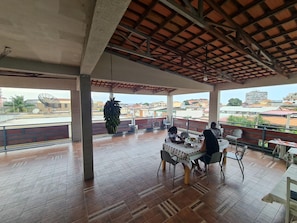 An outdoor dining area with a tiled floor, a table with chairs, and a view of the cityscape.