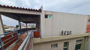 A balcony with a wooden floor, metal railings, and a view of the cityscape. - Guest House Sleeps 14 With Terrace (Luanda)