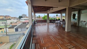 An outdoor terrace with tiled flooring, a covered seating area, and a view of the surrounding buildings. - Guest House Sleeps 14 With Terrace (Luanda)