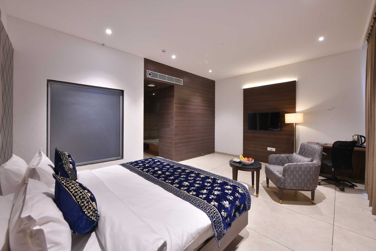 Een hotelkamer met een bed, een stoel, een bureau en een kleine tafel.