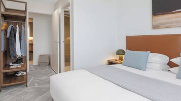 A hotel room with a bed, a nightstand with a lamp, a wardrobe, and a painting on the wall.